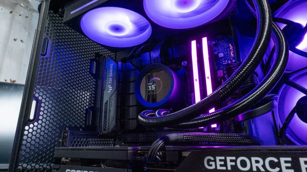 Intérieur d’un PC gamer avec watercooling AIO, RAM RGB violette, carte mère ASUS TUF Gaming et carte graphique GeForce RTX