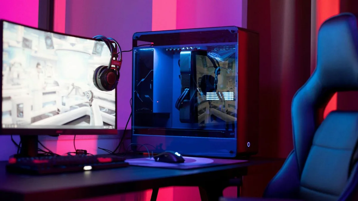 Setup de PC gamer avec écran, casque et fauteuil dans une chambre éclairée en violet