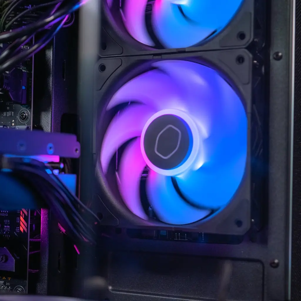 Gros plan sur l'un des ventilateurs Cooler Master du PC gamer Aqua, affichant un éclairage ARGB circulaire aux nuances de bleu, rose et violet