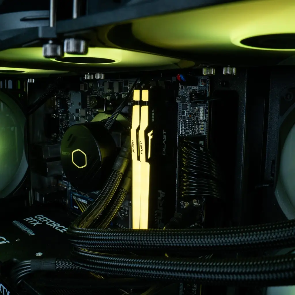Waterblock Cooler Master avec son liseré jaune et les barrettes de RAM Kingston FURY DDR5 illuminées, cœur battant du PC gamer Fuego