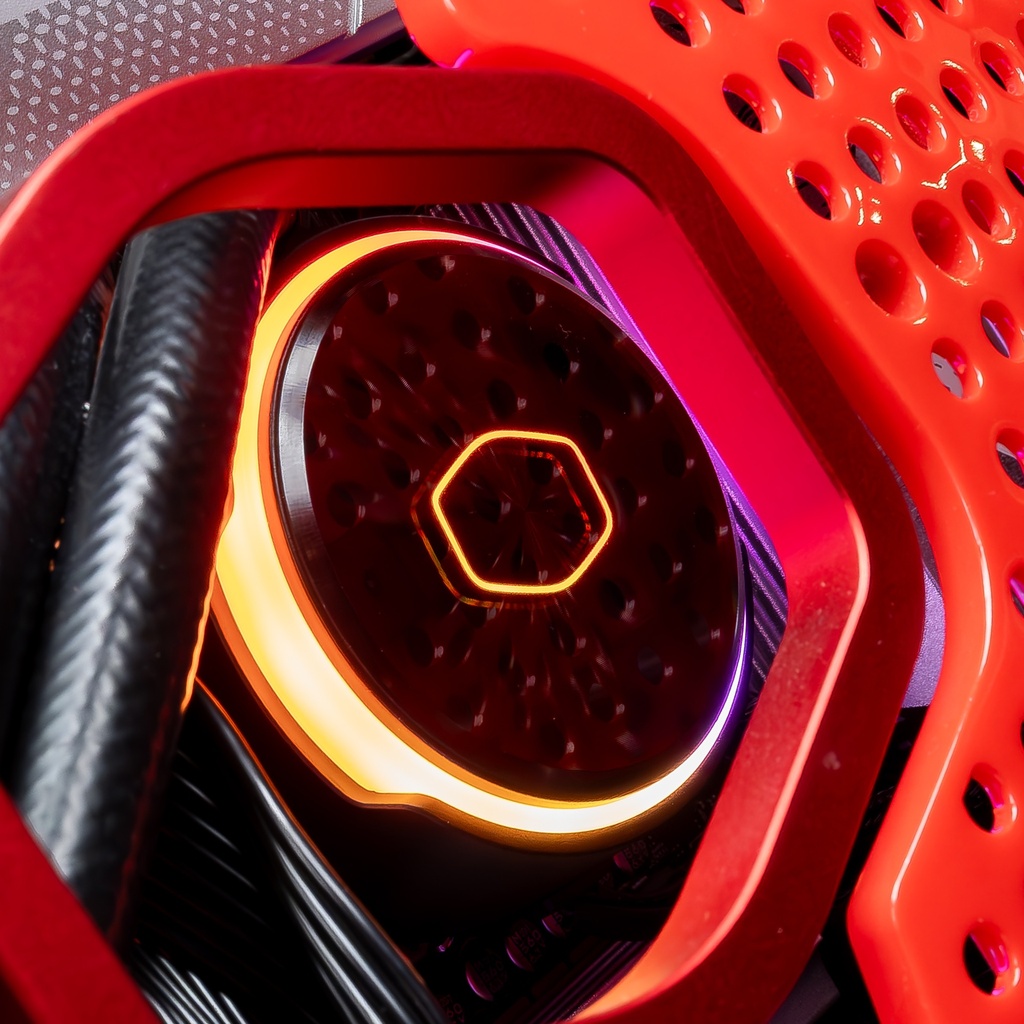 Vue rapprochée du waterblock Cooler Master avec éclairage circulaire orange à travers la structure perforée rouge du PC gamer Sneaker X GEFORCE RTX™ 5070 Ti
